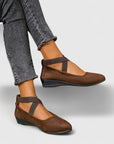 Brown wedge ballet flats with ankle strap and cross straps, paired with rolled jeans.