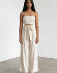 Beige strapless wide-leg jumpsuit with tied waist and sleeveless bodice
