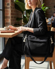 Black corduroy tote bag with tassel zipper pulls and wide shoulder strap