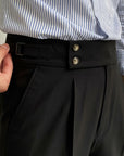 Men's high-waisted straight-leg tailored trousers in black, close-up of waistband buttons