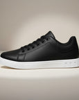Black low-top trainers with lace-up front, white midsole and textured outsole