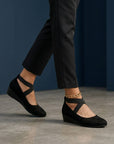 Black wedge ballet flats with ankle strap and cross strap detail, closed toe.
