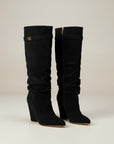 Black knee-high slouch boots with gold buckle tab at top shaft