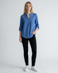 Denim-blue linen blouse with V-neck and button placket, three-quarter rolled sleeves.