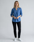 Blue linen blouse with V-neck and button placket, three-quarter sleeves folded at cuffs.
