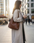 Brown slouchy shoulder bag with gold buckle strap, worn on shoulder