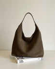 Olive-brown shoulder bag with open top and short handles on display.