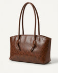 Textured brown leather tote bag with long handles and metal hardware
