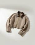Cropped beige knit cardigan with dark collared neckline, zip front, ribbed hem cuffs