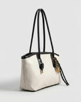 Off-white tote bag with long black handles and braided tassel charm