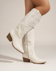 White suede cowboy boots with western stitching, side pull tab, and block heel