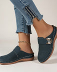 Navy blue slip-on slippers with metal buckle, perforated upper, and chain anklet.