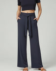 Dark blue relaxed wide-leg trousers with tie waist and draped front.