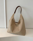 Beige shoulder bag with open top and short handles, hanging on display.