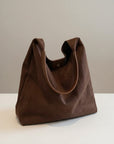 Dark brown shoulder bag with open top, curved seams, and short handles.