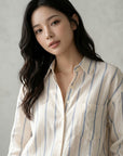 Striped button-up blouse with collar and buttons, cream with blue vertical stripes.