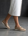 Beige slip-on loafers with gold bit accents and textured uppers, rubber sole.