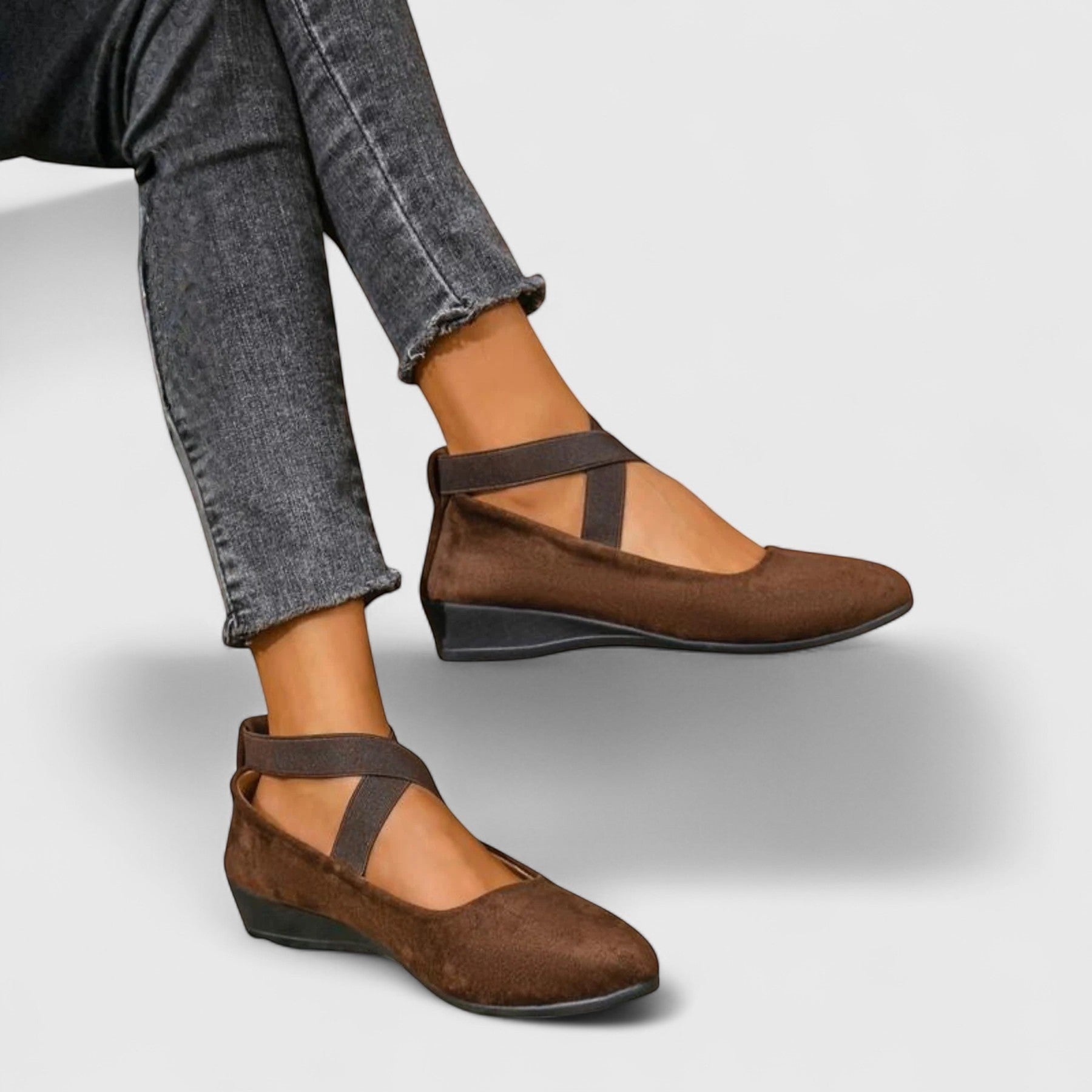 Brown wedge ballet flats with ankle strap and cross straps, paired with rolled jeans.