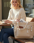 Cream corduroy tote bag with tassel accents and zip-close top pocket