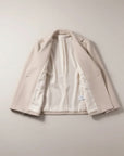 Beige double-breasted jacket laid open, showing lining, lapels, and inner placket
