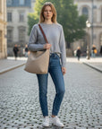 Taupe shoulder bag with open top and short handles, carried on shoulder.