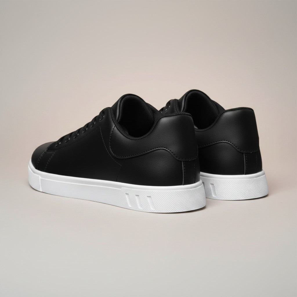 Black low-top trainers with heel tab and white rubber sole, rear view