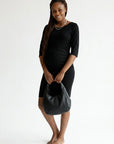 Black fitted maternity midi dress with ruched belly panel and three-quarter sleeves.