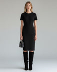 Black knee-high slouch boots on model, pull-on style with gold buckle detail