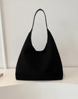 Black minimalist shoulder bag with open top and short handles on white surface.