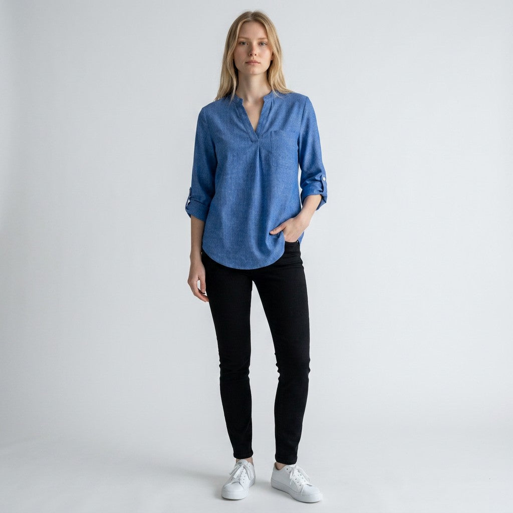 Denim-blue linen blouse with V-neck and button placket, three-quarter rolled sleeves.