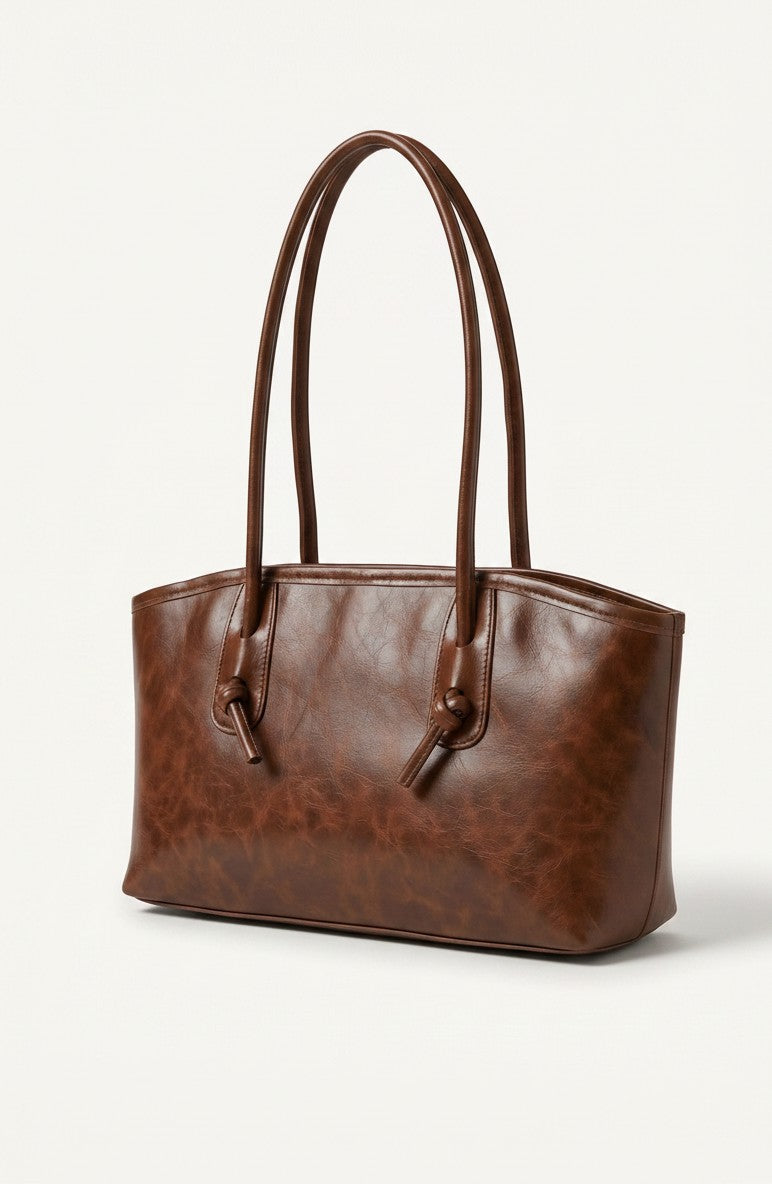 Textured brown leather tote bag with long handles and metal hardware