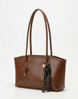 Textured brown tote bag with long handles and braided tassel charm