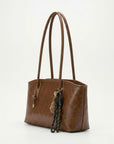 Textured brown leather tote bag with long handles and braided tassel key charm