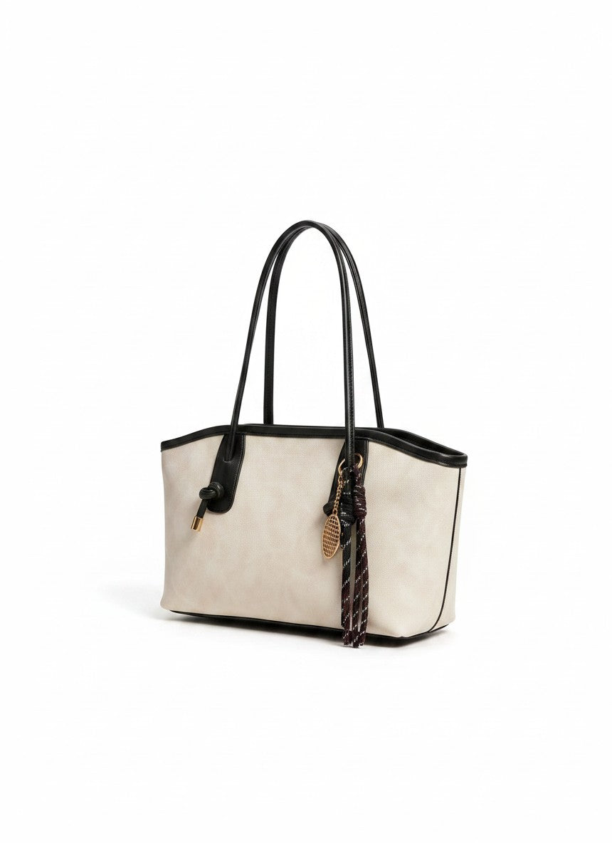 Off-white and black tote bag with long handles and braided tassel charm