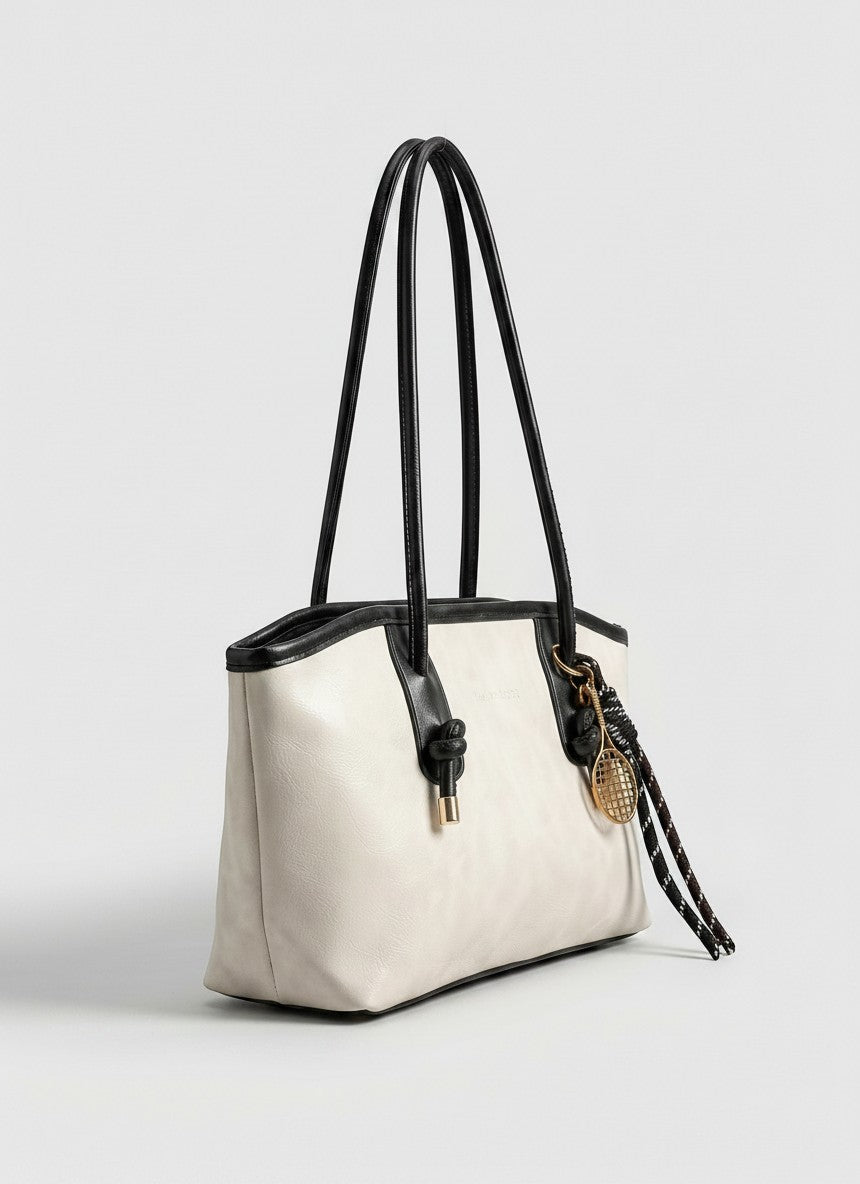 Off-white tote bag with long black handles and braided tassel charm