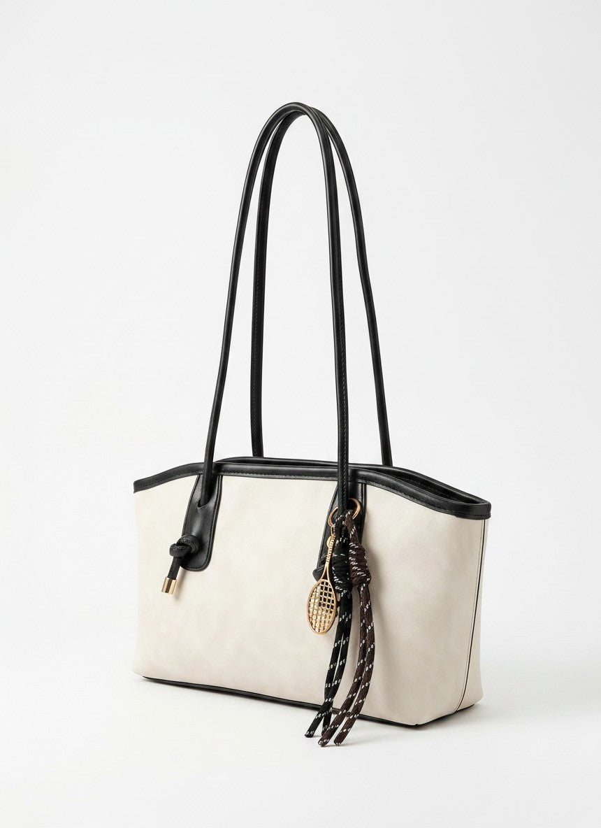 Off-white tote bag with black handles and braided tassel key charm