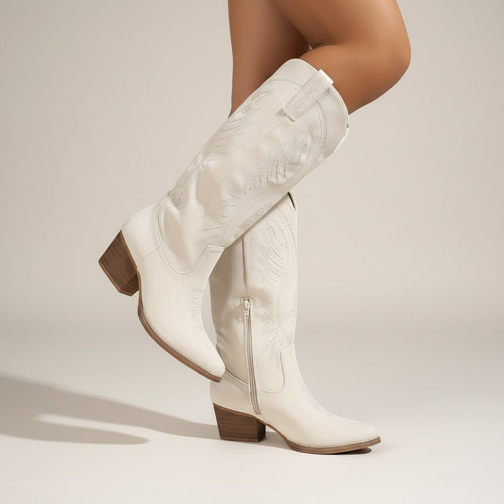 White suede cowboy boots with western stitching, side pull tab, and block heel