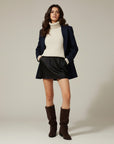Brown knee-high chunky heel boots worn with short dress, suede-look