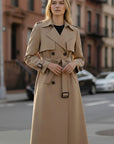 Beige women’s trench coat with double-breasted front, belt, epaulets, and flap pockets.