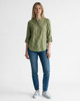 Green linen blouse with V-neck and button placket, three-quarter sleeves rolled at cuffs.