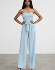 Light blue strapless wide-leg jumpsuit with tied waist, full-body front view