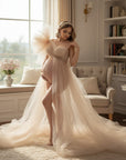 Beige sheer tulle maternity gown with off-shoulder bodice and flowing layered skirt