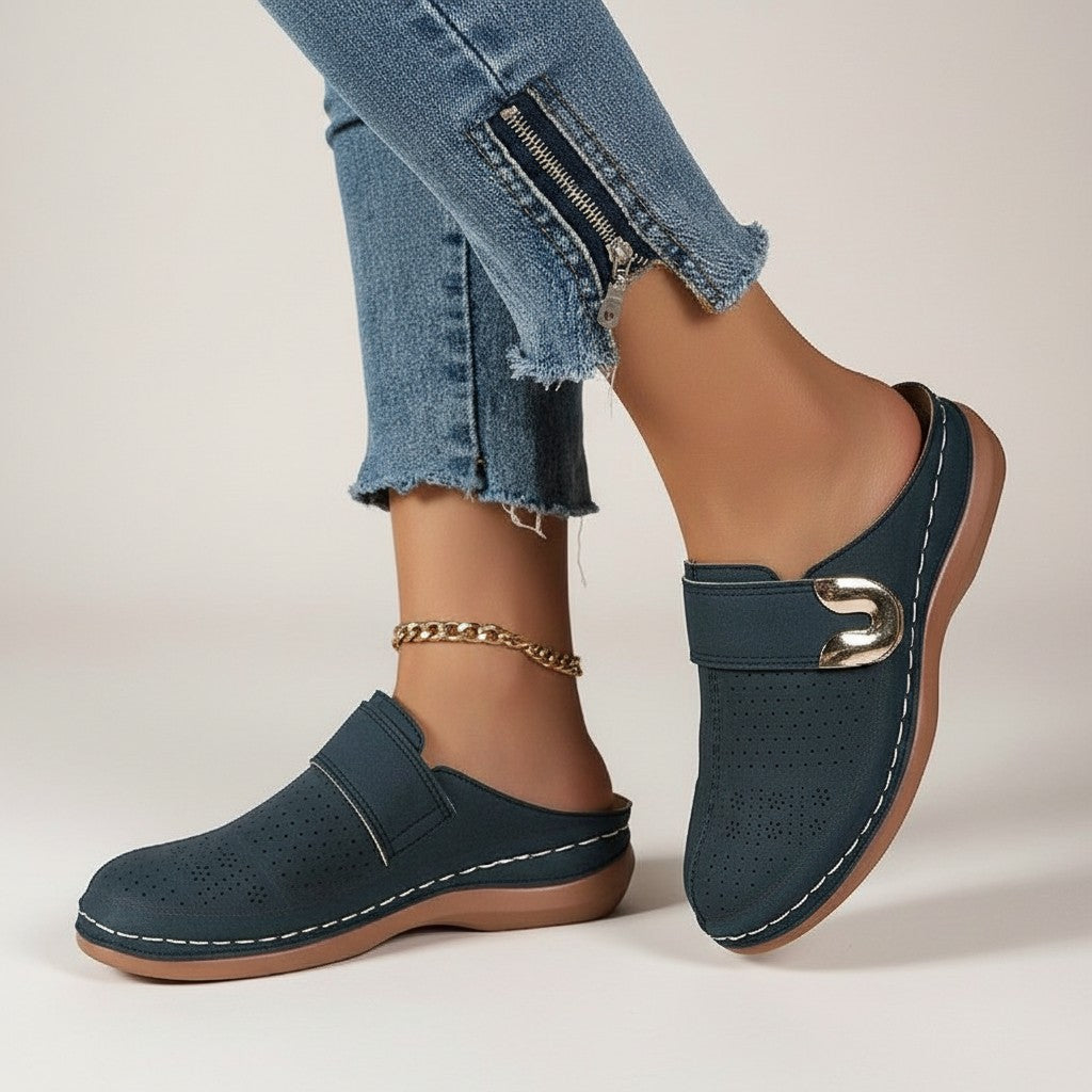 Navy blue slip-on slippers with metal buckle, perforated upper, and chain anklet.