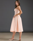 Peach fitted midi dress with adjustable spaghetti straps and softly gathered skirt