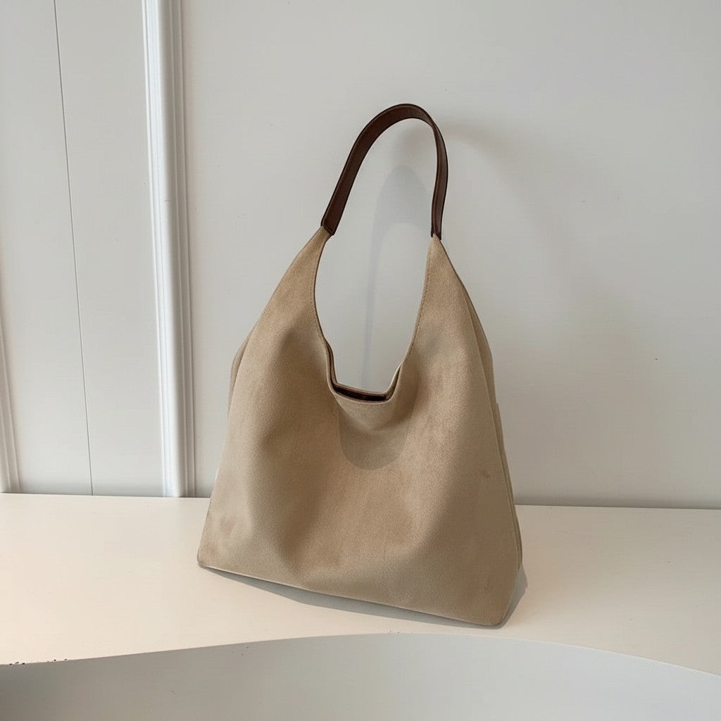 Beige shoulder bag with open top and short handles, hanging on display.