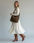 Brown soft shoulder bag with open-top crescent shape and short handles.