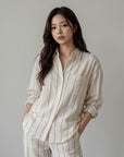 Striped button-up blouse with collar and pocket, cream with blue vertical stripes, button front.