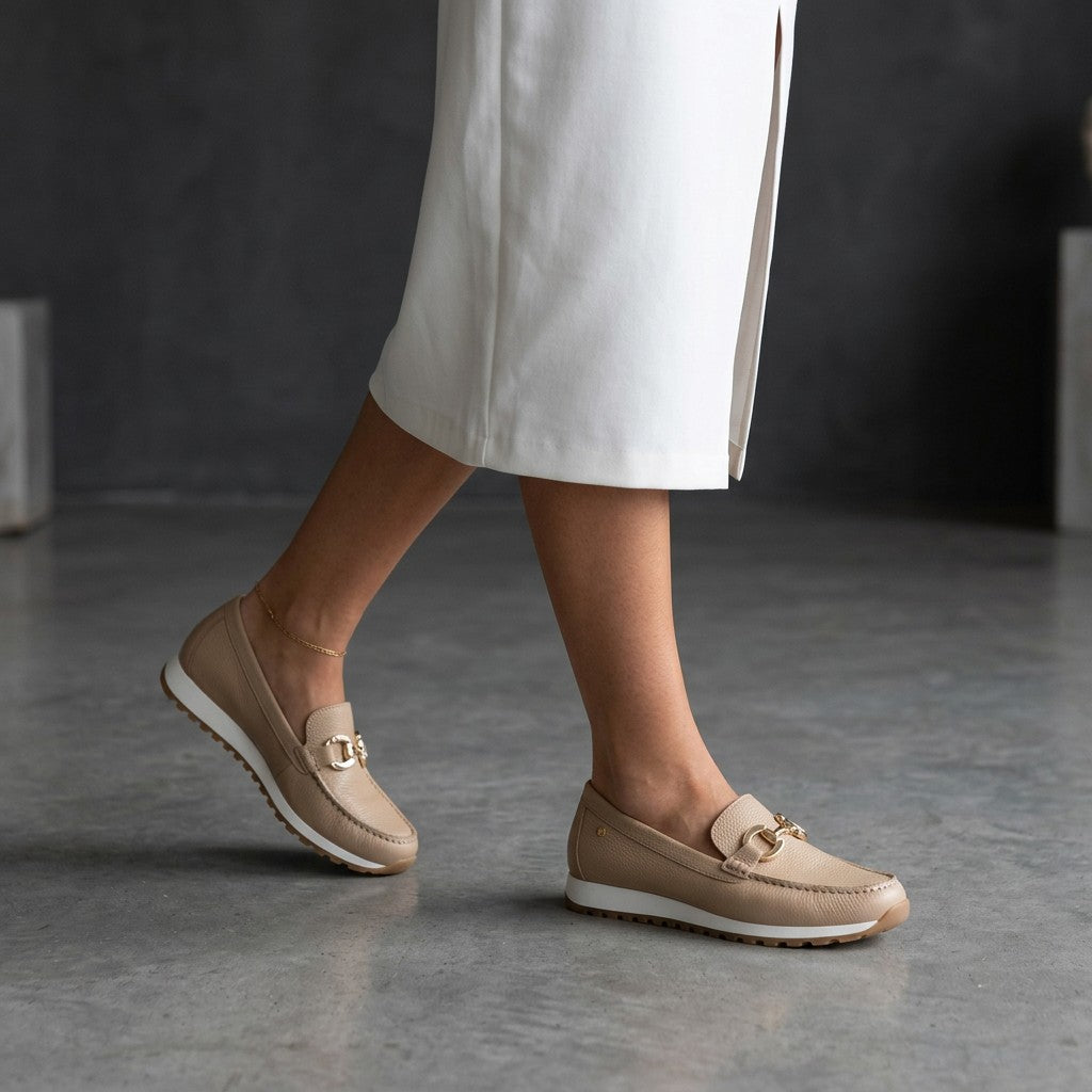 Beige slip-on loafers with gold bit accents and textured uppers, rubber sole.