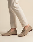 Beige suede loafers with horsebit detail on feet, almond toe slip-on